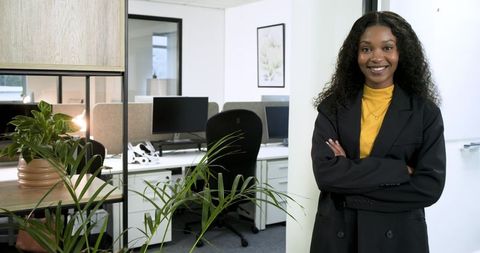 Confident businesswoman standing amid modern office desks