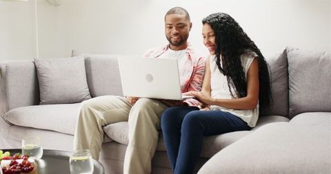 Diverse Couple Using Laptop on Couch, Joyful Online Interaction