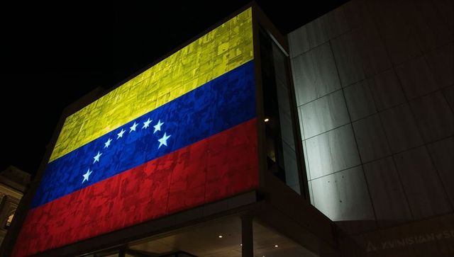 Projecting venezuelan flag on modern building facade at night with textured concrete light