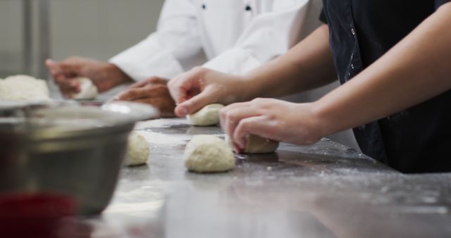 Two diverse female chefs preparing dough and talking in restaurant kitchen. Working in a busy restaurant kitchen.