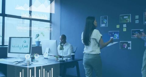 Businesswoman reviewing reports in collaborative modern office with data visualizations
