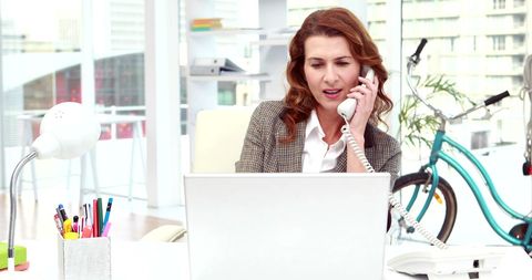 Businesswoman Multitasking with Laptop and Phone in Modern Office - Download Free Stock Images Pikwizard.com