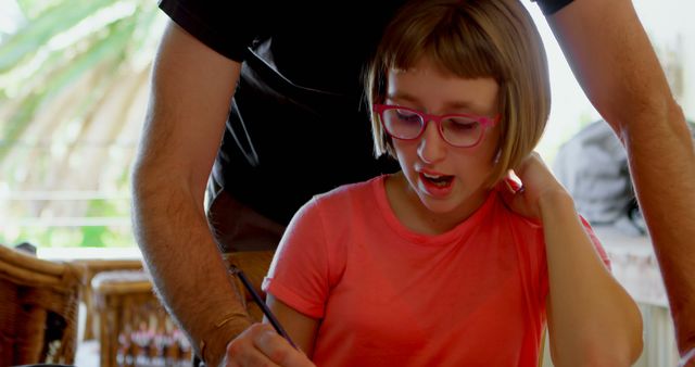 Child wearing pink glasses, surprising expression, parent helping with homework in indoor residential setting. Suitable for content related to education, homeschooling techniques, parent-child bonding, and learning disabilities.