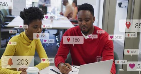 Team collaborating over laptop with social media notifications overlay in modern office