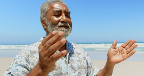 Senior Man Meditating on Beach with Eyes Closed