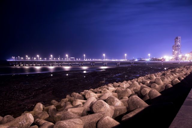 Night Cityscape with Illuminated Pedestrian Bridge and Seaside Rock Formation - Download Free Stock Photos Pikwizard.com