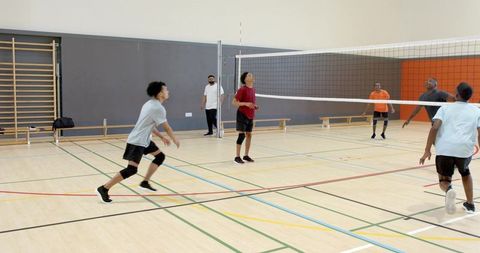 Diverse male athletes practicing indoor volleyball team drills receiving ball