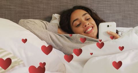 Woman Smiling While Texting in Bed with Digital Hearts