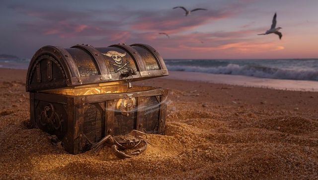 Pirate treasure chest glowing golden on sandy beach at sunset with skull emblem and crab