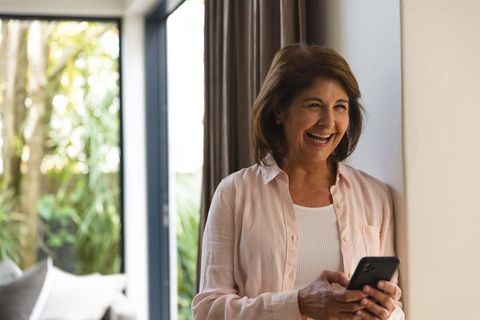 Senior Woman Smiling While Holding Smartphone at Home