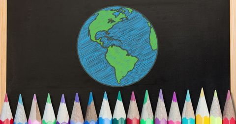Colorful pencils and illustrated globe on blackboard