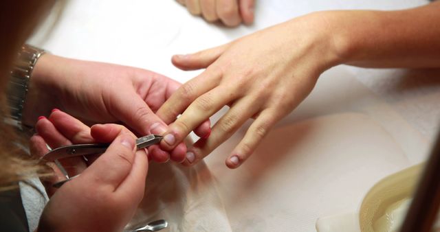Nail technician removing cuticles from customers nails at the nail salon