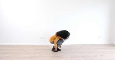 Young Woman in Yellow Sweater Crouching Indoors