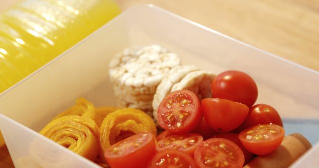 A healthy lunchbox filled with cherry tomatoes, rice cakes, and spiral-cut vegetables, with copy space. Ideal for promoting nutritious eating habits and meal planning for all ages.