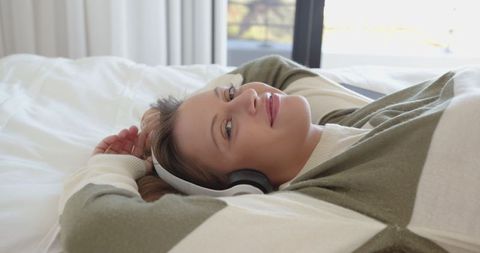 Woman Relaxing on Bed Listening with Headphones in Cozy Bedroom