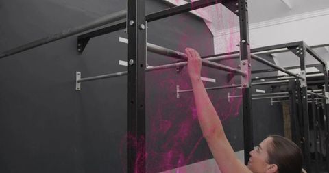 Woman reaching and gripping pull-up bar in gym training for strength and focus
