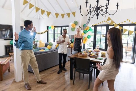 Joyful friends celebrating around decorated cake at home party