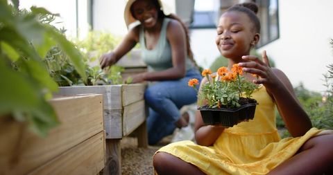 Mother and daughter gardening together in lush backyard garden