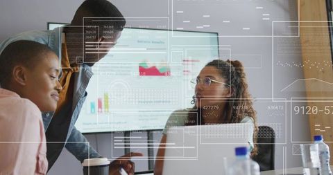 Diverse team collaborating around laptop with data overlays in office presentation meeting