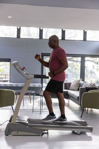 Senior Man Exercising on Treadmill in Modern Living Room
