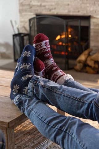 Couple resting in festive knit socks with denim jeans near roaring fireplace warmth