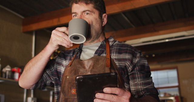 Carpenter Drinking Coffee and Using Digital Tablet in Workshop - Download Free Stock Images Pikwizard.com