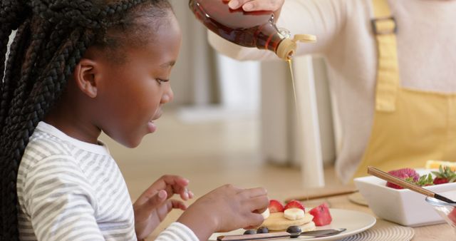 Child Eating Breakfast with Syrup Being Poured on Fruits and Pancakes - Download Free Stock Images Pikwizard.com