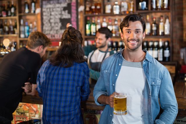 Man enjoying a beer in a lively bar setting, perfect for illustrating social gatherings, nightlife, and leisure activities. Ideal for use in advertisements for bars, pubs, or social events, as well as articles on socializing and relaxation.
