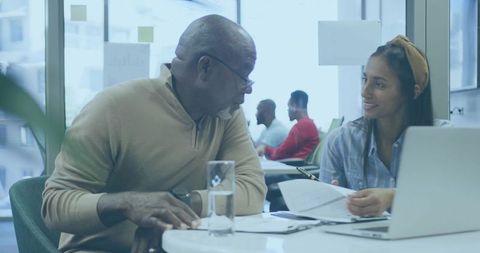Senior Mentor and Young Professional Reviewing Documents at Modern Coworking Table
