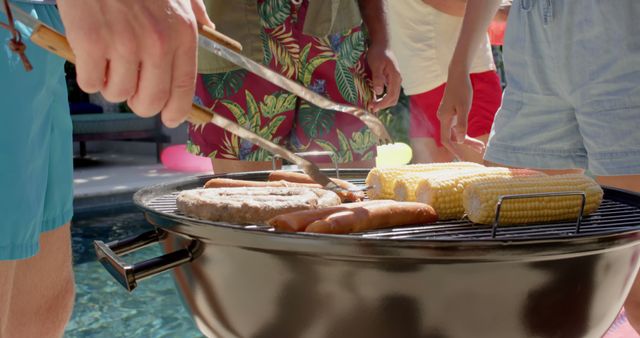People enjoying a sunny day by the pool while grilling food. The scene features sausages and corn on the grill, indicating an outdoor gathering filled with fun and relaxation. Useful for promotions related to summer activities, outdoor events, and food pairing ideas.