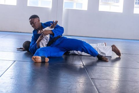 Male athletes practicing ground grappling technique in dojo