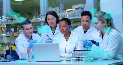 Multidisciplinary research team collaborating at lab bench reviewing data on laptop