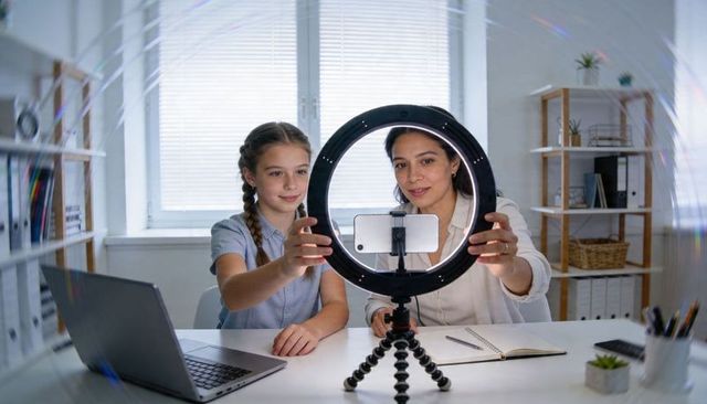 Parent and Daughter Creating Video Content with Ring Light and Smartphone in Home Office
