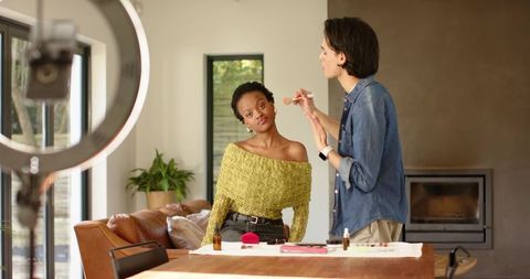 Makeup artist applying makeup with ring light in bright living room tutorial