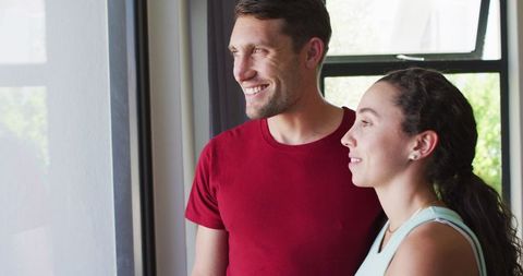 Happy Couple Looking Out Window at Home in Relaxed Atmosphere