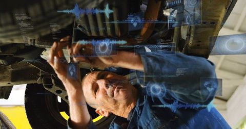 Mechanic diagnosing undercarriage with digital hud overlays while repairing suspension