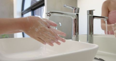 Hands lathering soap at bathroom sink for hygiene