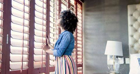 Curly-Haired Woman in Colorful Dress Gazing Out Window with Natural Light