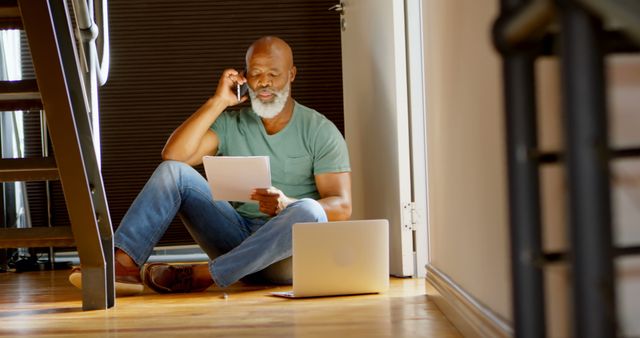 Senior man using phone and reading document at home with laptop - Download Free Stock Images Pikwizard.com