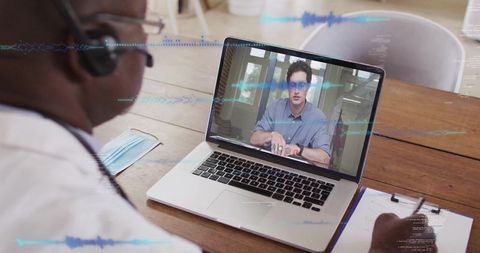 Doctor Conducting Virtual Consultation Using Laptop at Office Desk
