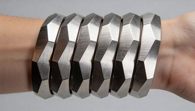 Stacked faceted steel bangles on wrist brushed metal geometric polygonal jewelry