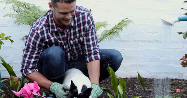 Young man kneeling in garden enjoying time with dog while planting flowers. Perfect for themes around gardening, nature, pet care, and outdoor activities. Suitable for illustrating bonding moments between pets and owners or promoting a healthy, active lifestyle.