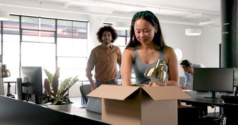 Colleagues unpacking box in modern office environment