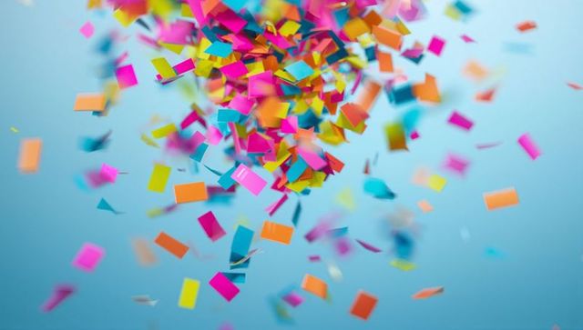 Swirling multicolored confetti cluster capturing motion blur over soft blue background