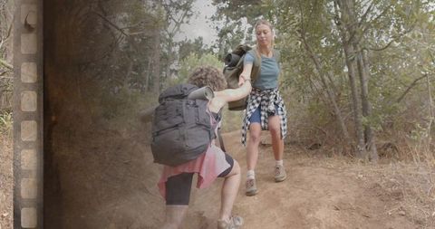 Helping hand hiking teamwork women climbing steep woodland trail with backpacks, filmstrip overlay
