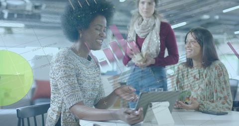 Diverse Women Collaborating on Digital Financial Data in Modern Office