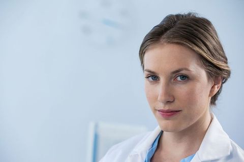 Smiling female doctor in clean exam room with lab coat and scrubs