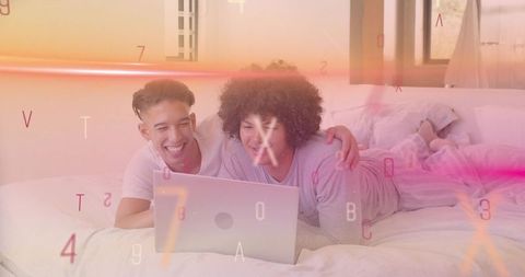 Two men relaxing on bed watching laptop with warm soft light and colorful digital overlay