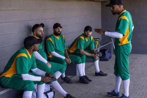 Baseball captain coaching teammates in dugout before game showing leadership and strategy