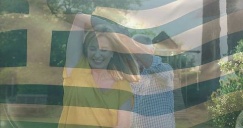 Joyful seniors dancing in garden with greek flag overlay